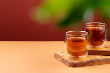 Two glass cups of black tea on beige table
