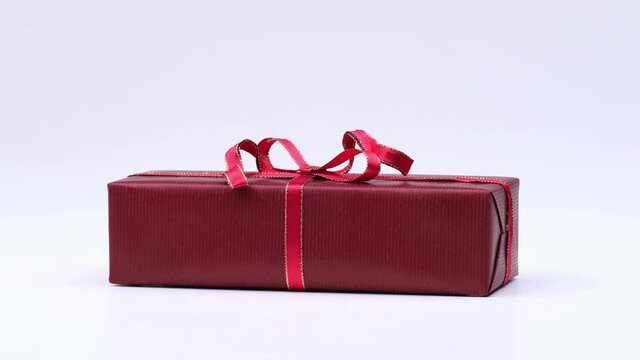 Wrapping christmas gift with red paper and red ribbon on white background. 4K stop motion animation.