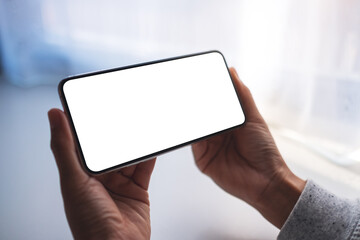 Mockup image of a woman holding mobile phone with blank white desktop screen