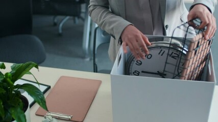 Unrecognizable woman standing at office desk starting her fisrt workday in company with takingsome items out of box