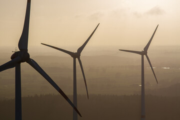 wind turbine, wind farm on a sunny misty morning shot from eye level, hub height with agricultural...