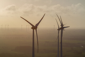 wind turbine, wind farm on a sunny misty morning shot from eye level, hub height with agricultural landscape below