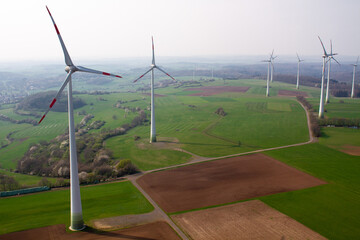 wind turbine, wind farm on a sunny misty morning shot from eye level, hub height with agricultural...