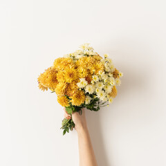 Flatlay of yellow and ginger fall wild flowers bouquet in women's hand isolated on white background. Flat lay, top view minimalistic floral composition. Valentine's Day, Mother's Day concept.