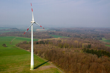 Fototapeta premium wind turbine, wind farm on a sunny misty morning shot from eye level, hub height with agricultural landscape below