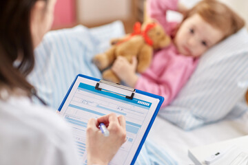 healthcare, medicine and people concept - close up of doctor with clipboard and little sick girl lying in bed at home