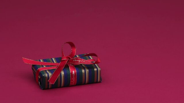 Christmas gits of different shapes and colours changing on red background. 4K, Stop motion animation loop.