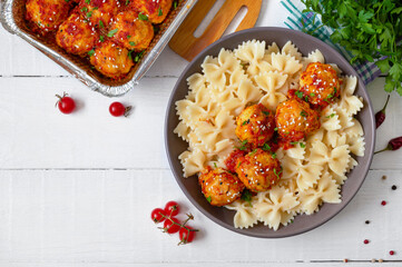 Farfalle pasta and chicken meatballs in tomato sauce. Top view.