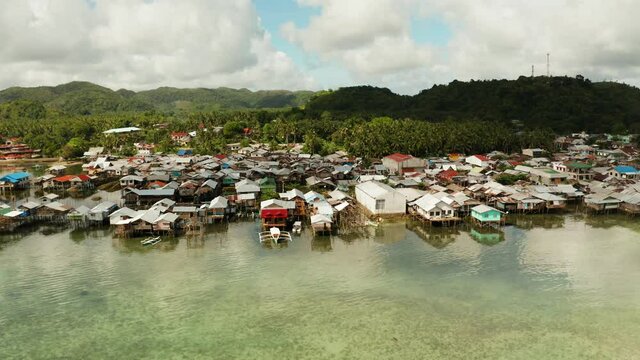 Fishing village with boats and slums with wooden houses, aerial drone. Dapa, Siargao, Philippines.