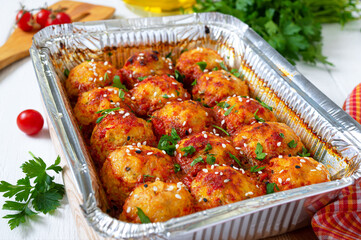 Meatballs in tomato sauce baked in an aluminum foil container. Diet meat dish.
