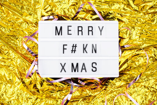 Light boxing with the words merry fkn xmas on a golden background. New Year's Eve and content.