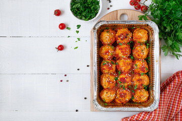 Meatballs in tomato sauce baked in an aluminum foil container. Diet meat dish. The top view. Copy space