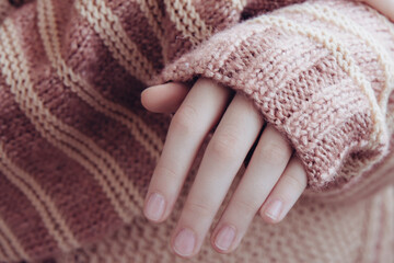 Woman in a beige soft warm knitted sweater folded her hands. Autumn soon