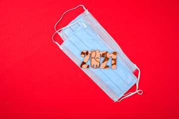 A face mask with a new year symbol on a red background. New year 2021 awareness. Coronavirus...