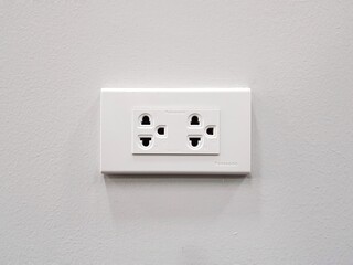 White electrical outlet socket on white plaster wall background.