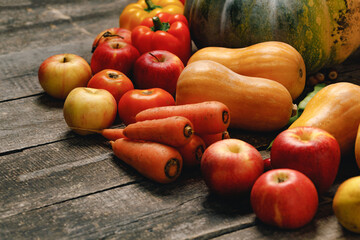 Pumpkins, carrots and red apples on wooden table
