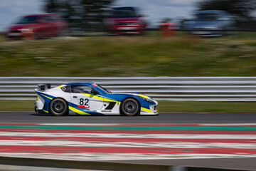 A panning shot of a racing car as it circuits a track.