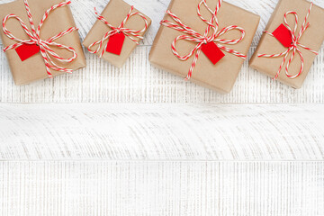 Christmas presents on the white wooden background with copy space. Top view of gift boxes in craft...