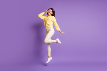 Photo portrait full body view of cheerful girl making v-sign near eye jumping up isolated on bright purple colored background