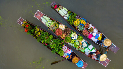 Obraz premium Aerial view famous floating market in Thailand, Damnoen Saduak floating market, Farmer go to sell organic products, fruits, vegetables and Thai cuisine, Tourists visiting by boat, Ratchaburi, Thailand