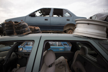 Damaged cars with missing engines, bonnets, doors, wheels or other parts. Awaiting dismantling, re-sale or recycling. At a vehicle graveyard.