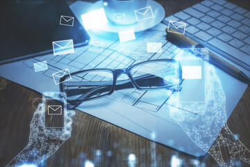 Flying envelop theme hologram with glasses on the table background. Electronic mail concept. Double exposure.