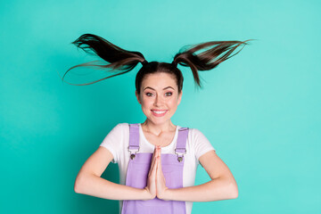 Photo of cute young girl hold arms beaming smile look camera wear violet overall isolated teal...