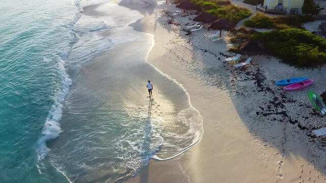 Junger Mann macht einen morgendlichen Strandspaziergang bei Sonnenaufgang