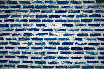 The texture of the brick wall of many rows of bricks painted in blue color. Grunge brick wall blue texture navy blue background