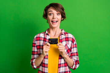 Photo of impressed cute short hairdo girl hold card wear orange cloth isolated over vivid green color background