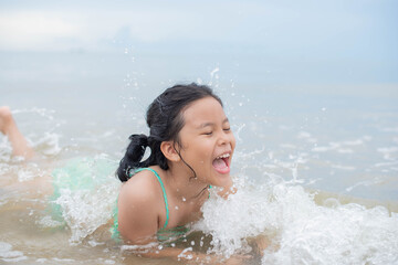 Happy laughing 8 year girl laying on sand beach. summer holidays. Child in nature with beautiful sea, sand and blue sky. Happy kids on vacations seaside..