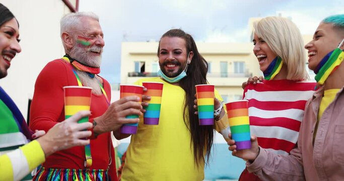 Happy gay people cheering with rainbow glasses at pride outdoor wearing face masks - Lgbt and love concept - Slow Motion