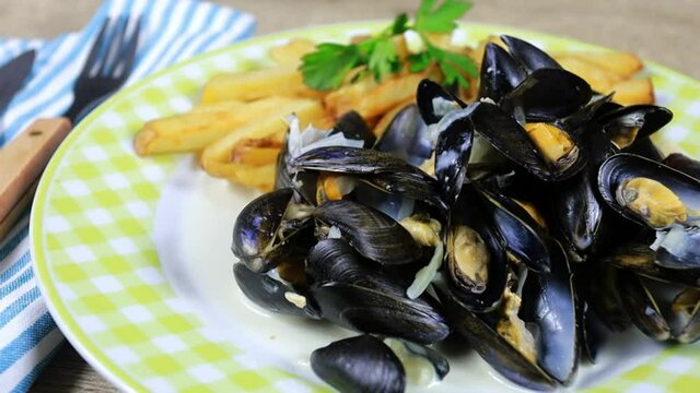 assiette de moules cuisin&eacute;es et frites sur une table