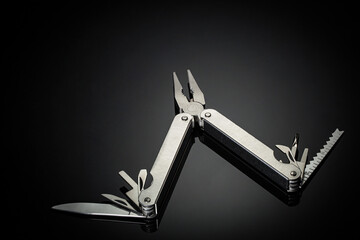 One multipurpose folding knife isolated on black background. multifunctional folding camping knife, screwdriver, scissor, knife, bottle opener, saw and others