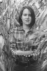 Black and white shot of Young woman farmer with corn harvest. Worker holding autumn corncobs. Farming and gardening