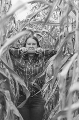 Black and white shot of Young woman farmer with corn harvest. Worker holding autumn corncobs. Farming and gardening