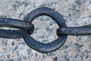 Old forged rusty chain with peeling paint on the background of paving stones.
