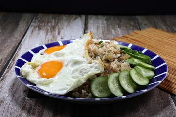 Traditional fried rice topping with double fried egg and sliced fresh cucumber on the plate. Famous special street food in Asia restaurant. 