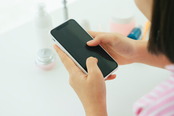 Beautiful young asian thai black short hair woman using smartphone in restroom.