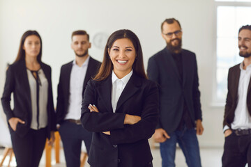 Happy smiling female company leader with team of employees standing in background