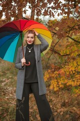 Blonde nice woman at autumn coat and colorful umbrella at park. Pretty plus size European lady