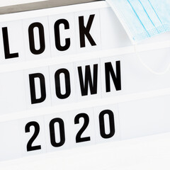 Light box with message lockdown 2020  and Surgical protective mask. Word of the Year 2020 is lockdown.