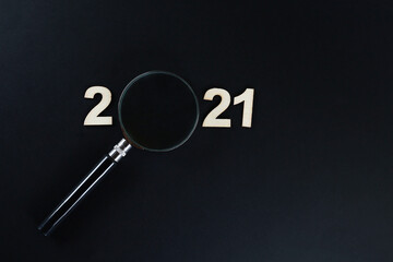 A magnifying glass and block letters in 2021 on black background