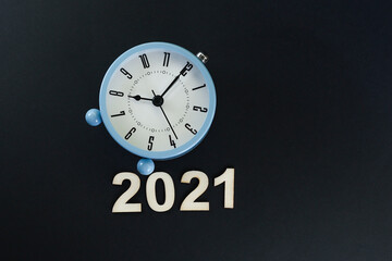 Block letters on the year 2021 with alarm clock on black background 