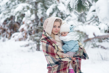 Fototapeta na wymiar Young mother of the family holding a little daughter in her arms, walking through the winter forest 