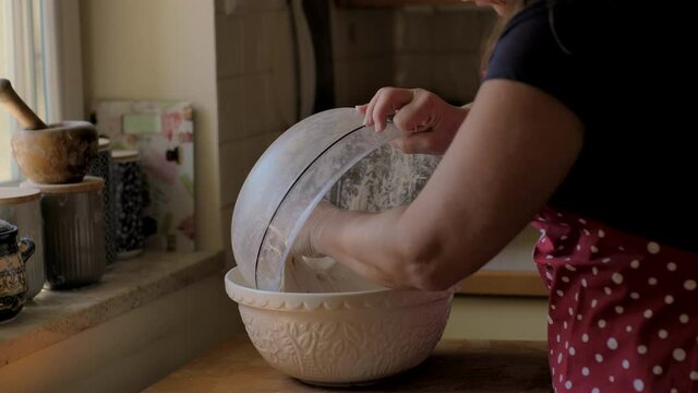 Close up of hands kneading sourdough bread, streaching the dough in bowl.