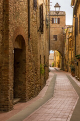 Fototapeta na wymiar The empty narrow winding back street of a historic hilltop town in Tuscany Italy.