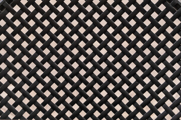 The black metal lattice back of an outdoor chair, forming a repeating pattern ideal for backgrounds