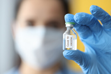 Doctor with protective medical mask holding bottle with covid-19 vaccine close-up. Prevention of disease coronavirus infection vaccination Concept