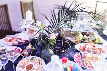 Close up of festive table setting with wine glasses, food and fresh fern